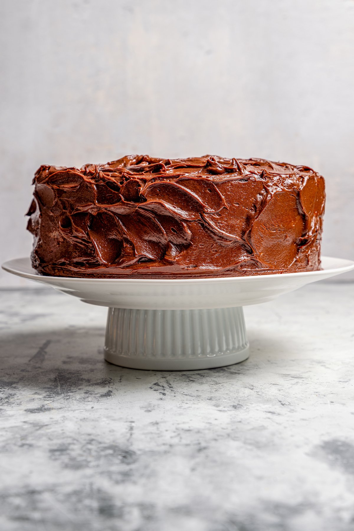 Whole cake with chocolate frosting on a cake stand.