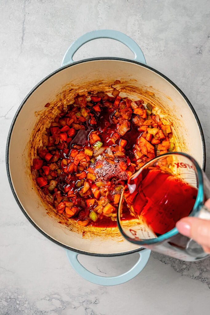 Pouring in the wine to deglaze the Dutch oven. 